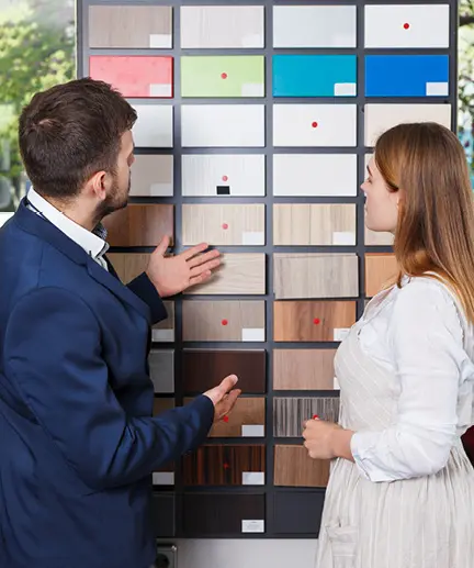 Fachverkäufer berät Kundin bei der Auswahl verschiedener Holzoberflächen.